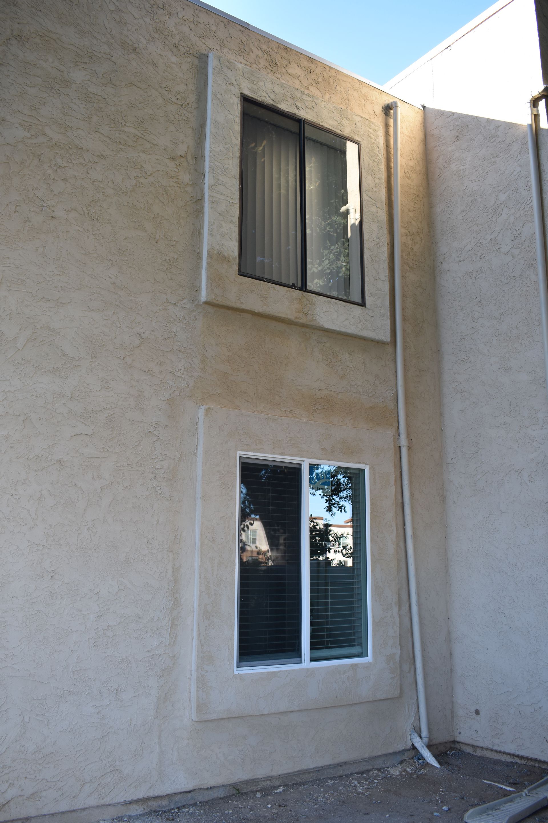 A building with two windows and a drainpipe on the side.