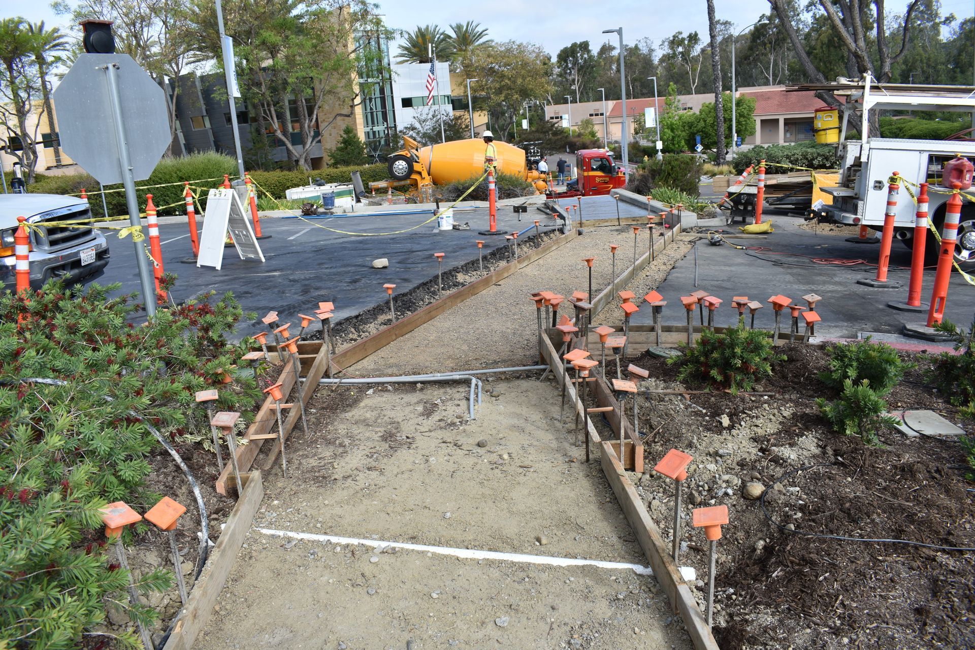 A concrete walkway is being built in a parking lot