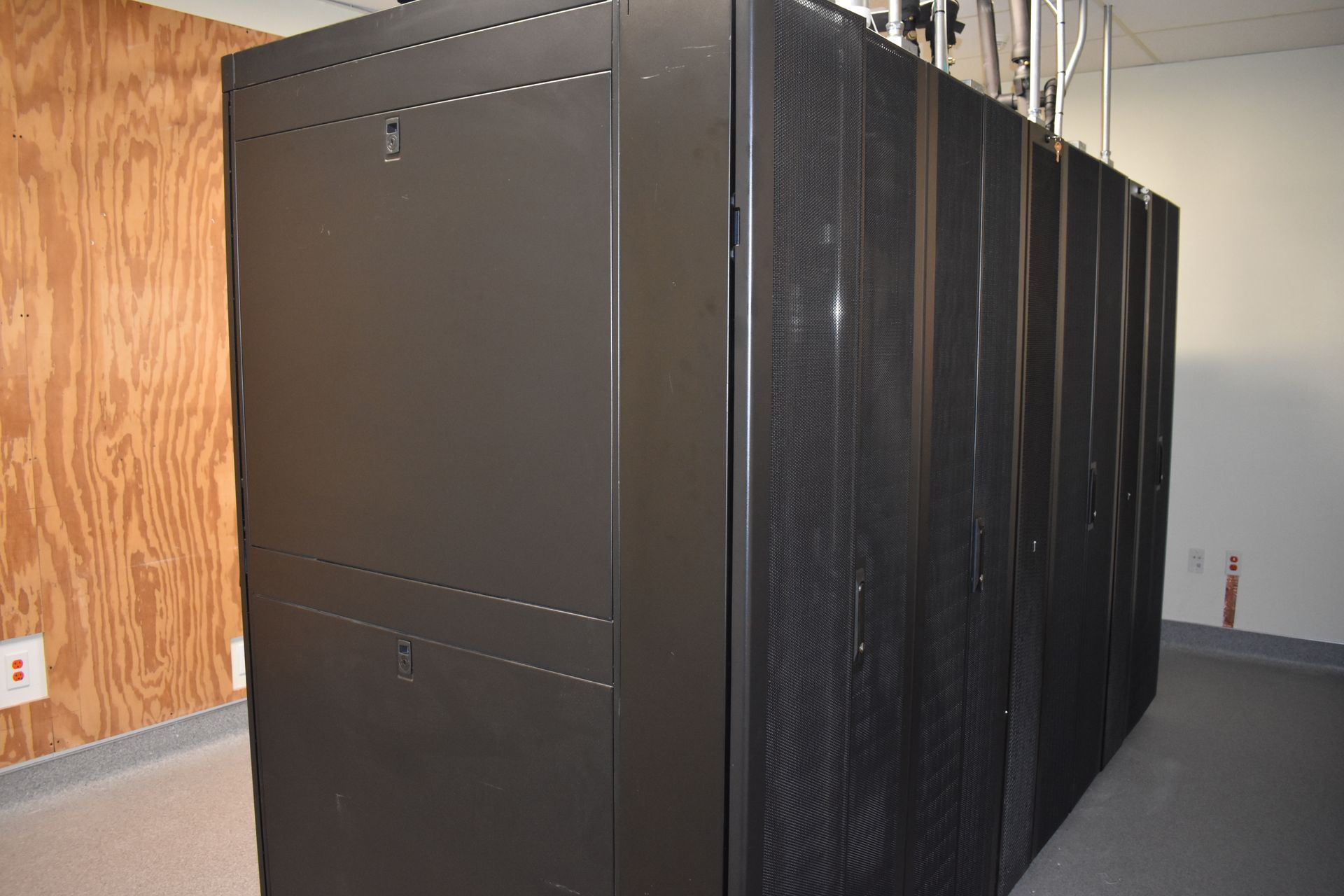 A row of black servers are lined up in a room.