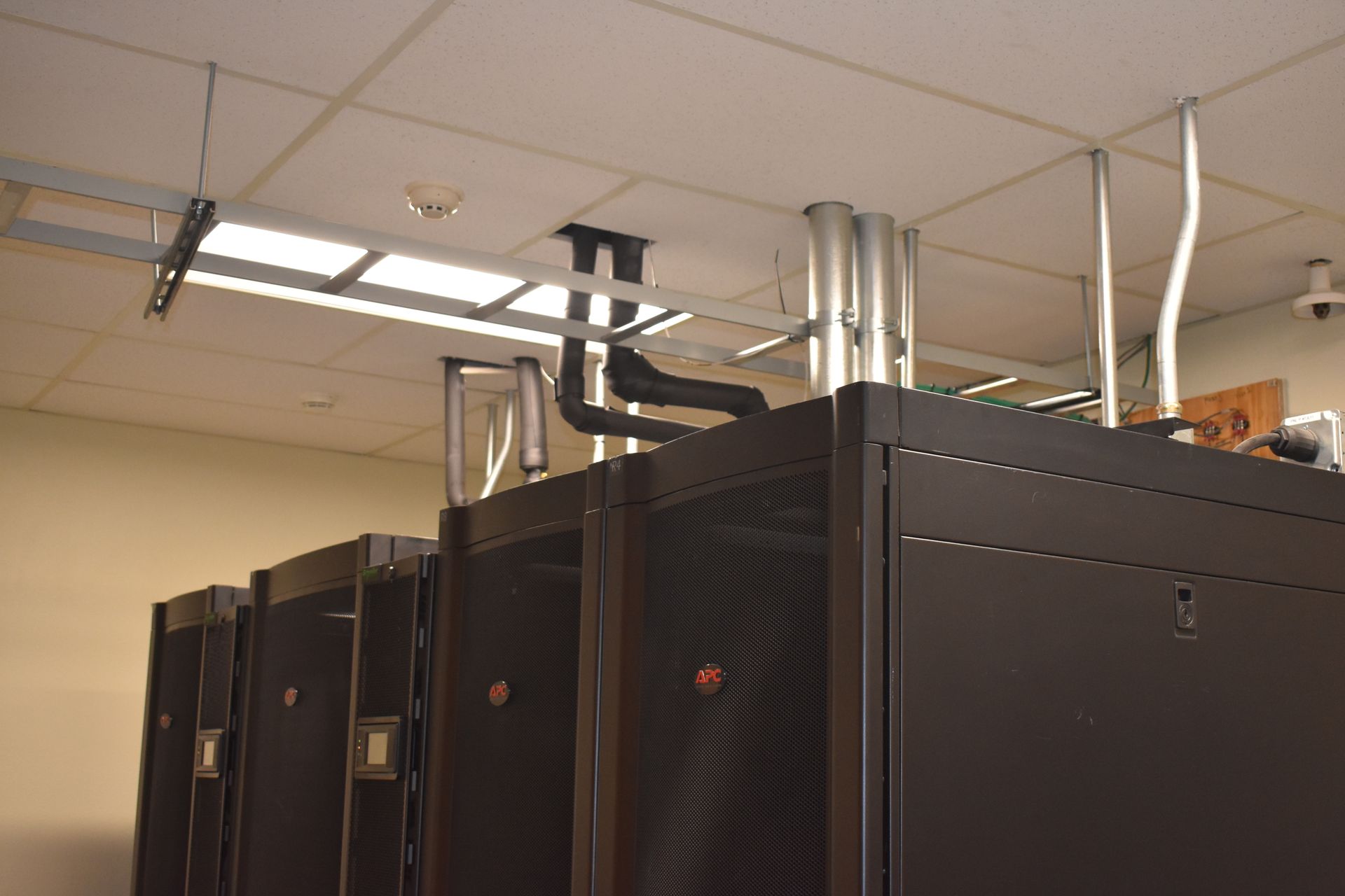 A room with a lot of servers and pipes hanging from the ceiling