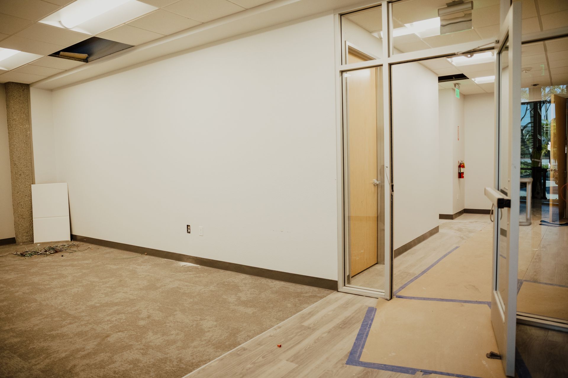 An empty room with a glass door and a white wall.