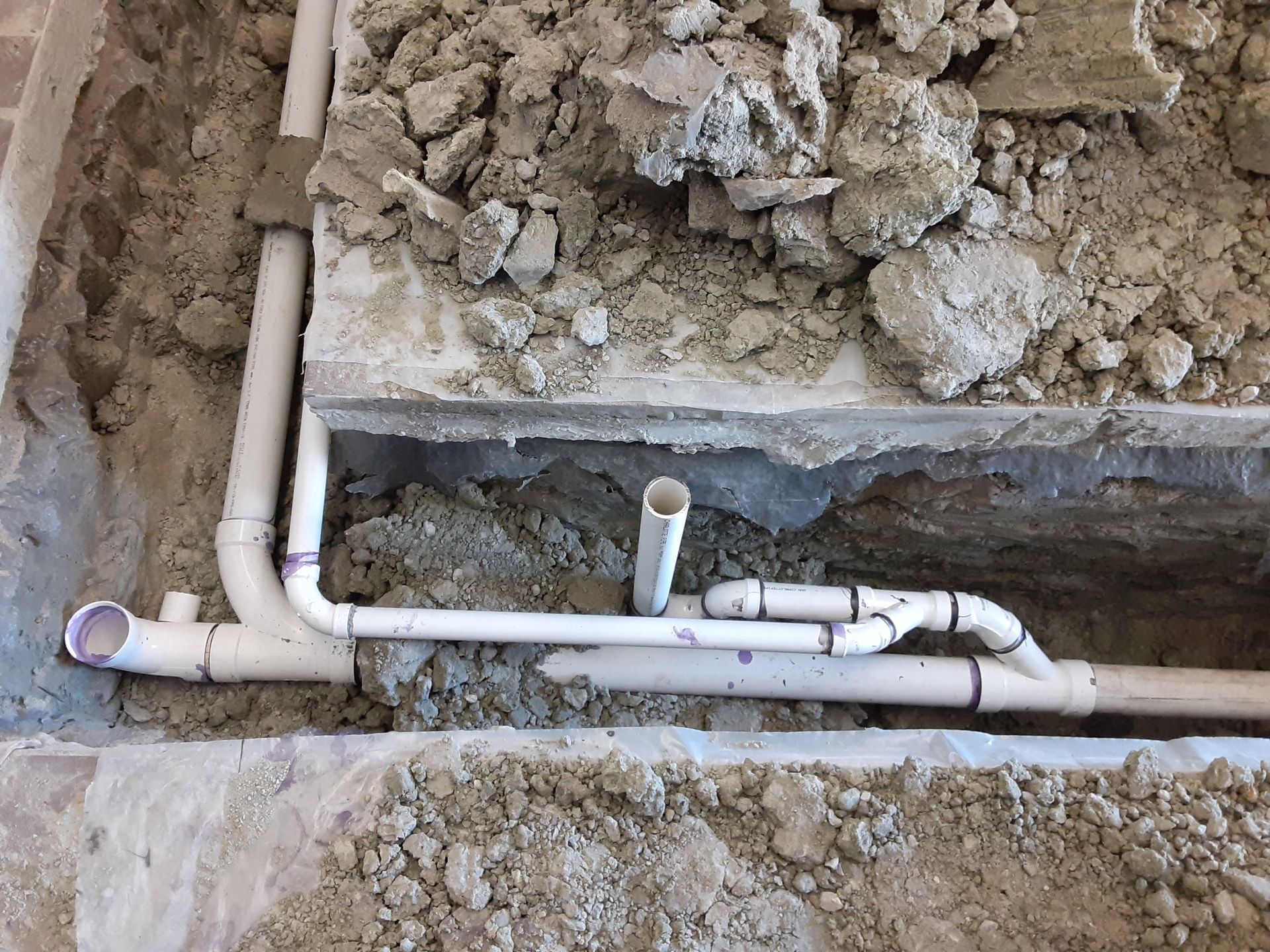 A bunch of pipes are laying in the dirt.