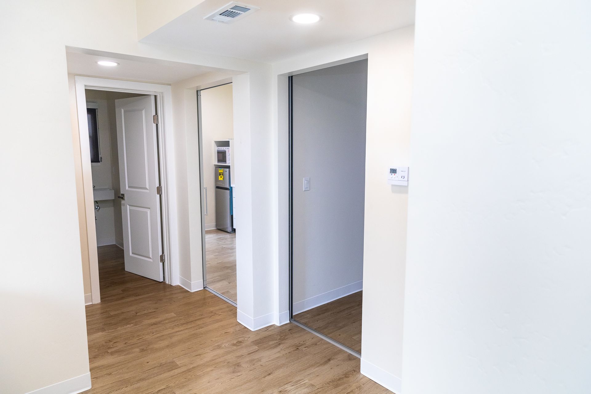 A hallway in a house with wooden floors and white walls.