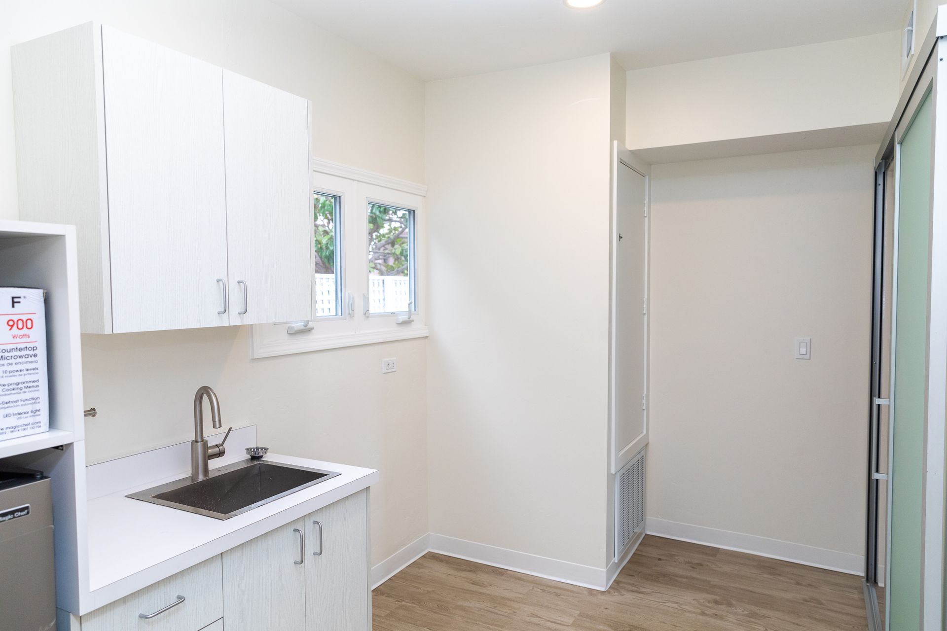 A kitchen with white cabinets , a sink , and a refrigerator.