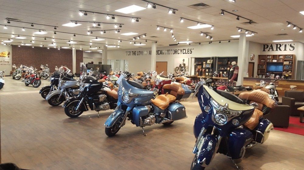 A row of motorcycles are parked in a showroom.