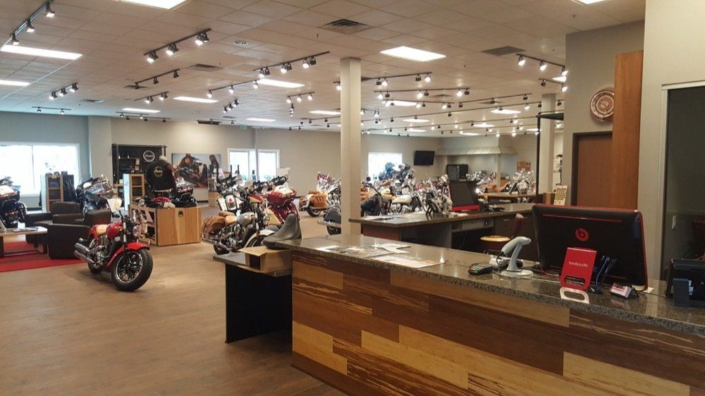 A motorcycle is parked in front of a counter in a motorcycle dealership.