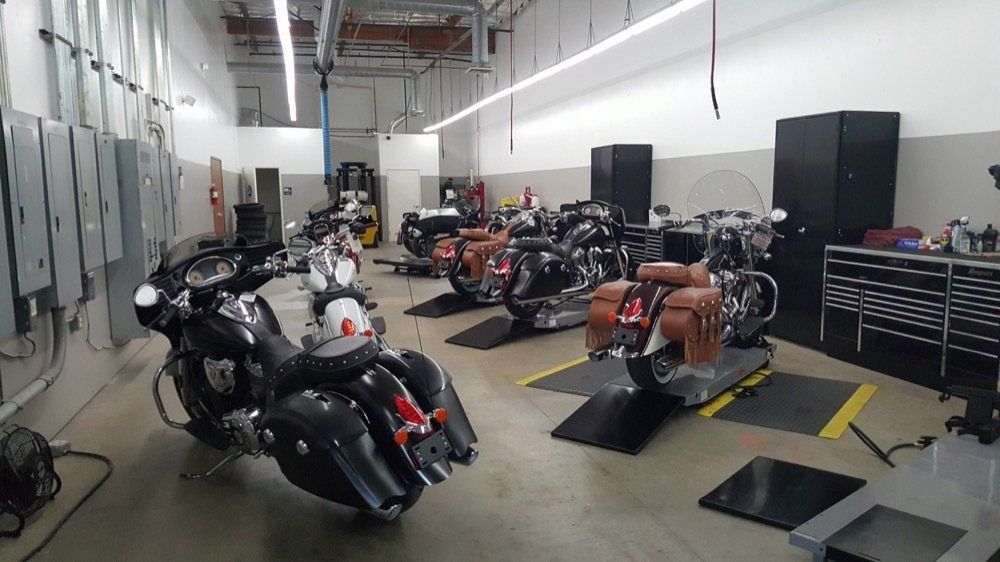A row of motorcycles are parked in a garage.