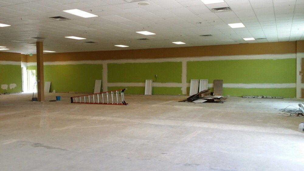 A large empty room with green walls and a ladder on the floor.