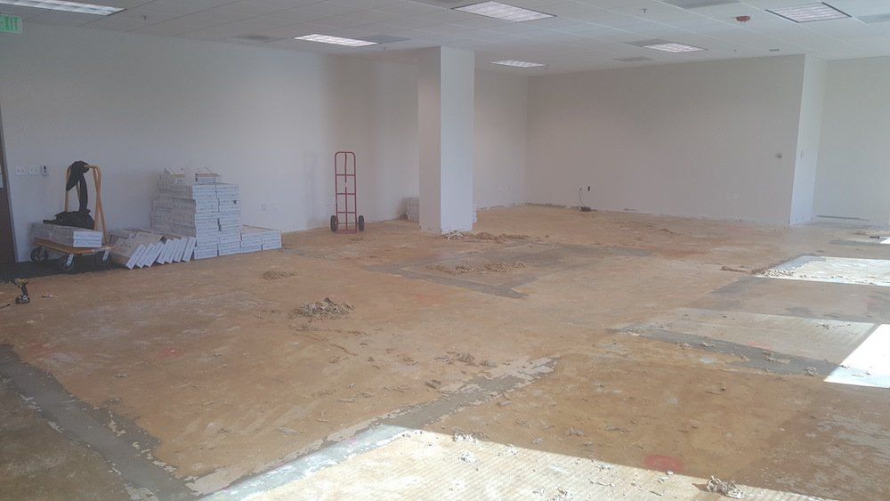 A large empty room with a wooden floor and white walls.