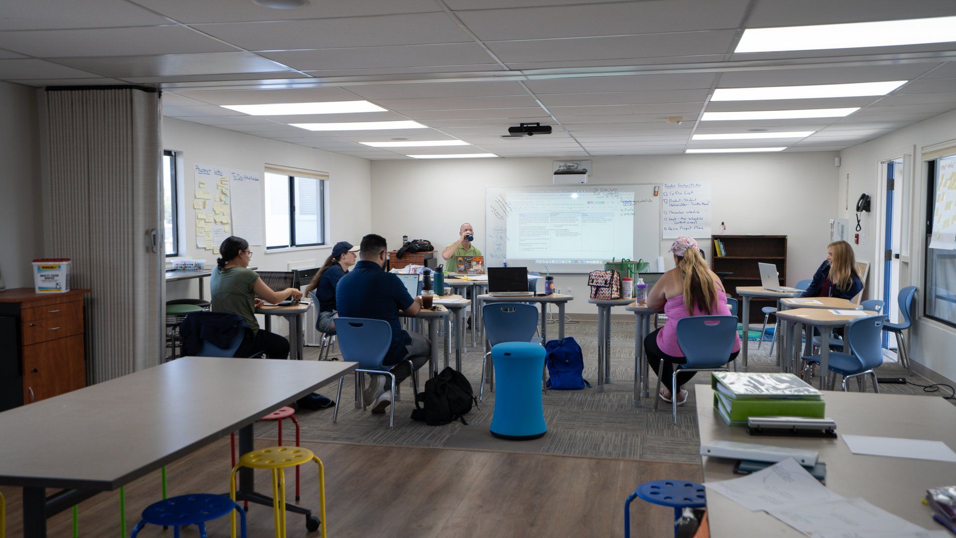 A group of people are sitting at tables in a classroom.