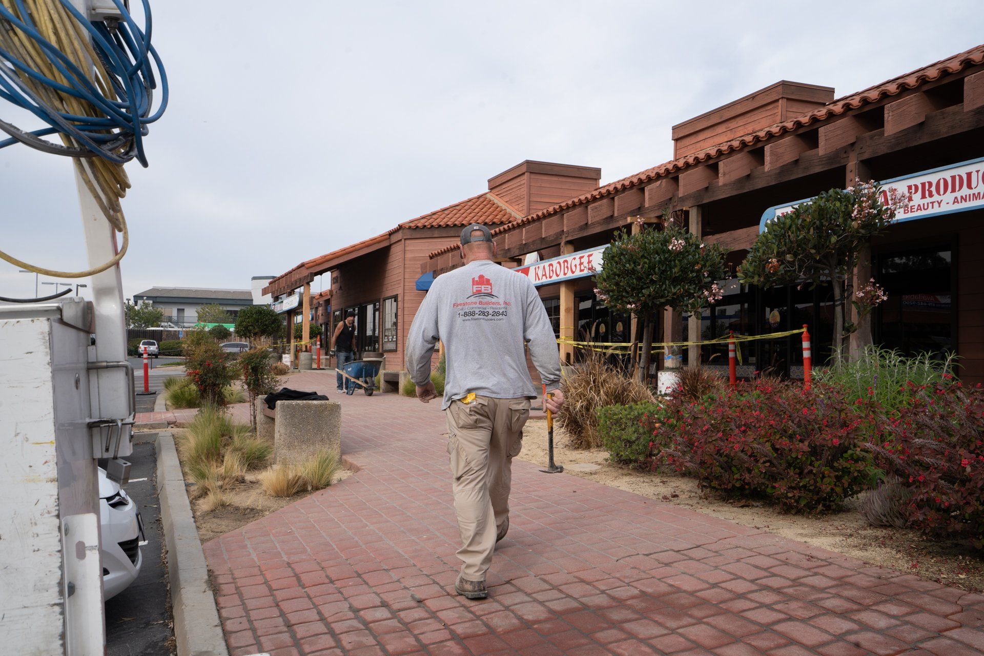A man is walking down a sidewalk in front of a building.