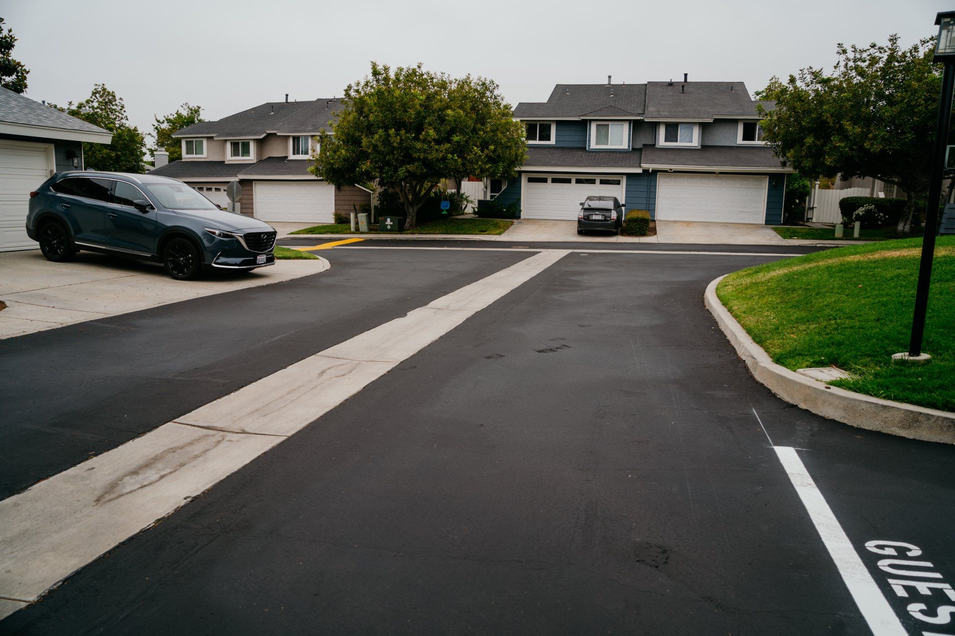 A black car is parked on the side of the road next to a sign that says guest