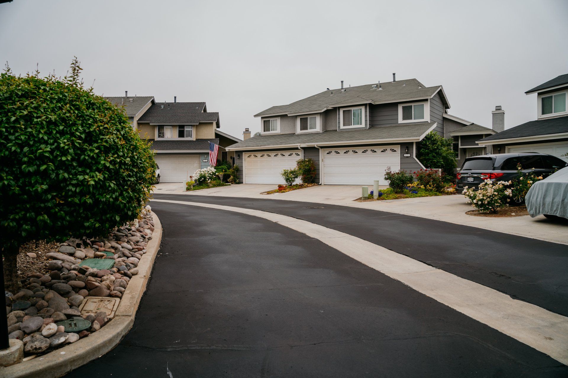 A car is parked on the side of the road in front of a row of houses