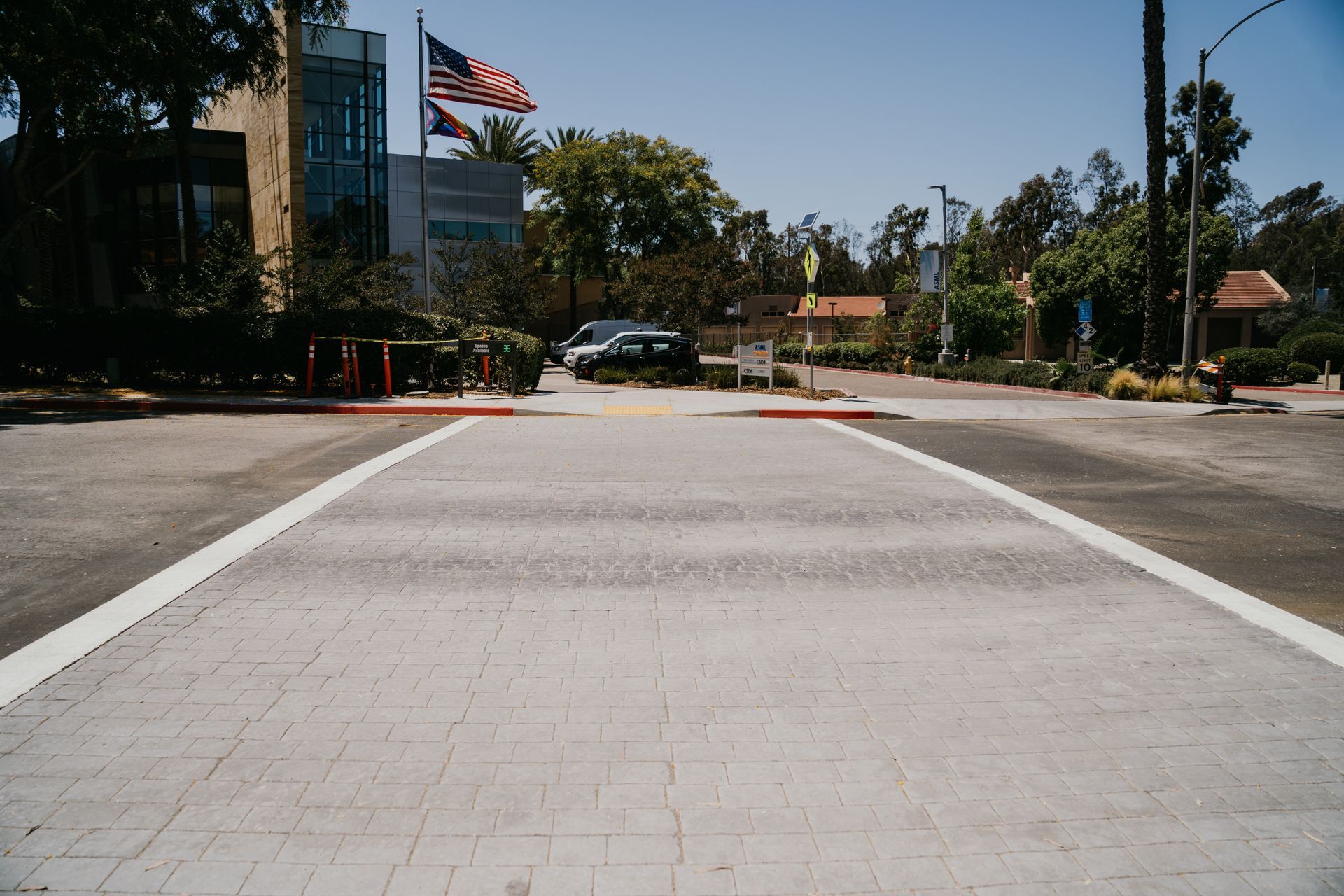 A crosswalk in front of a building with an american flag flying in the background.