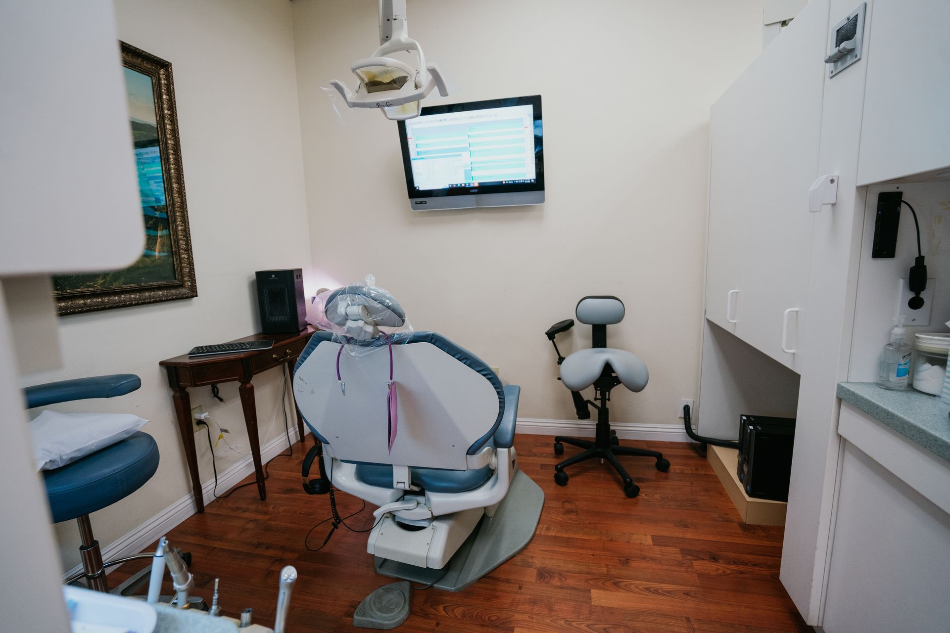 A dental office with a dental chair and a television on the wall.