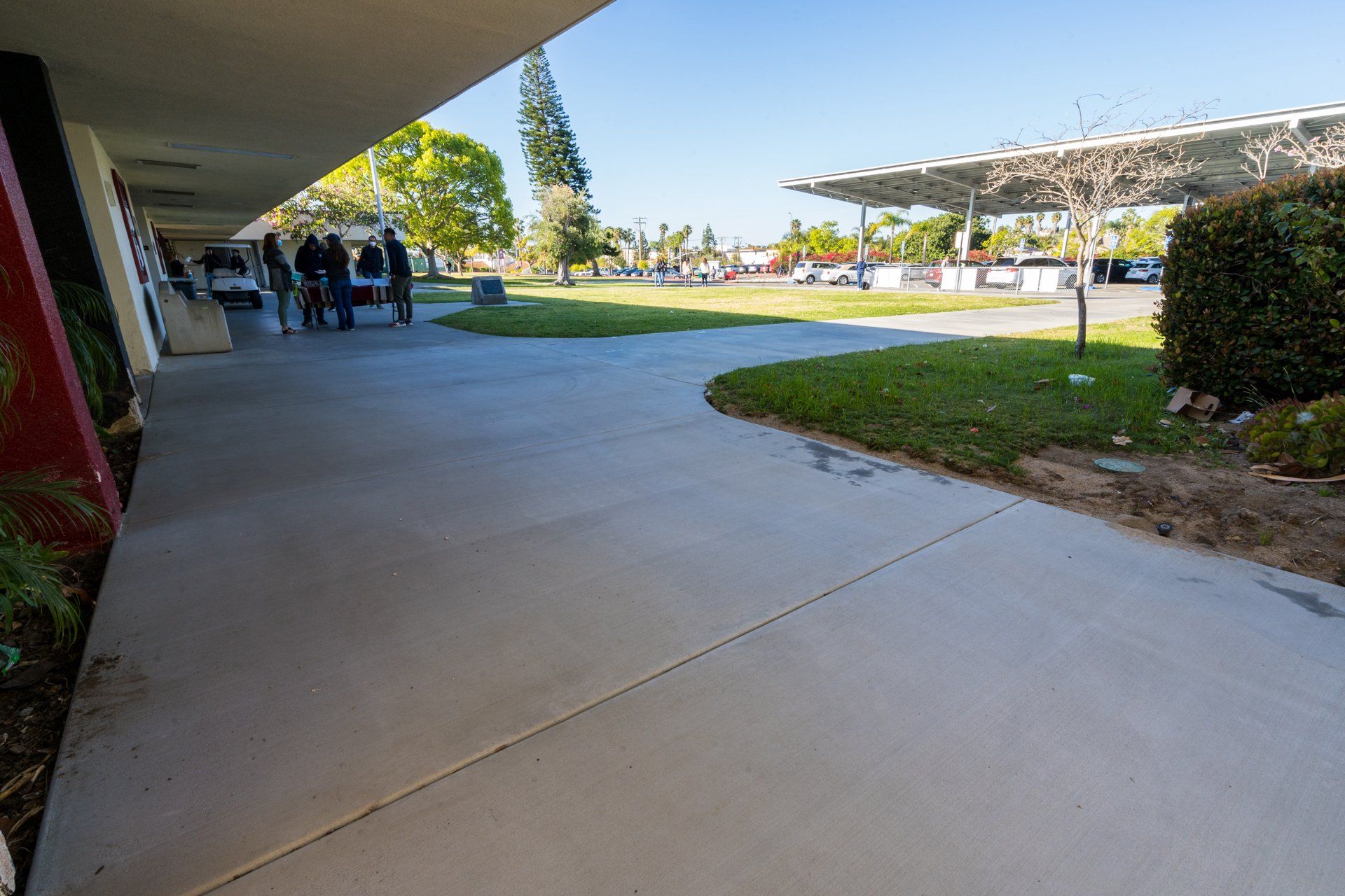 A group of people are standing on a sidewalk in front of a building.