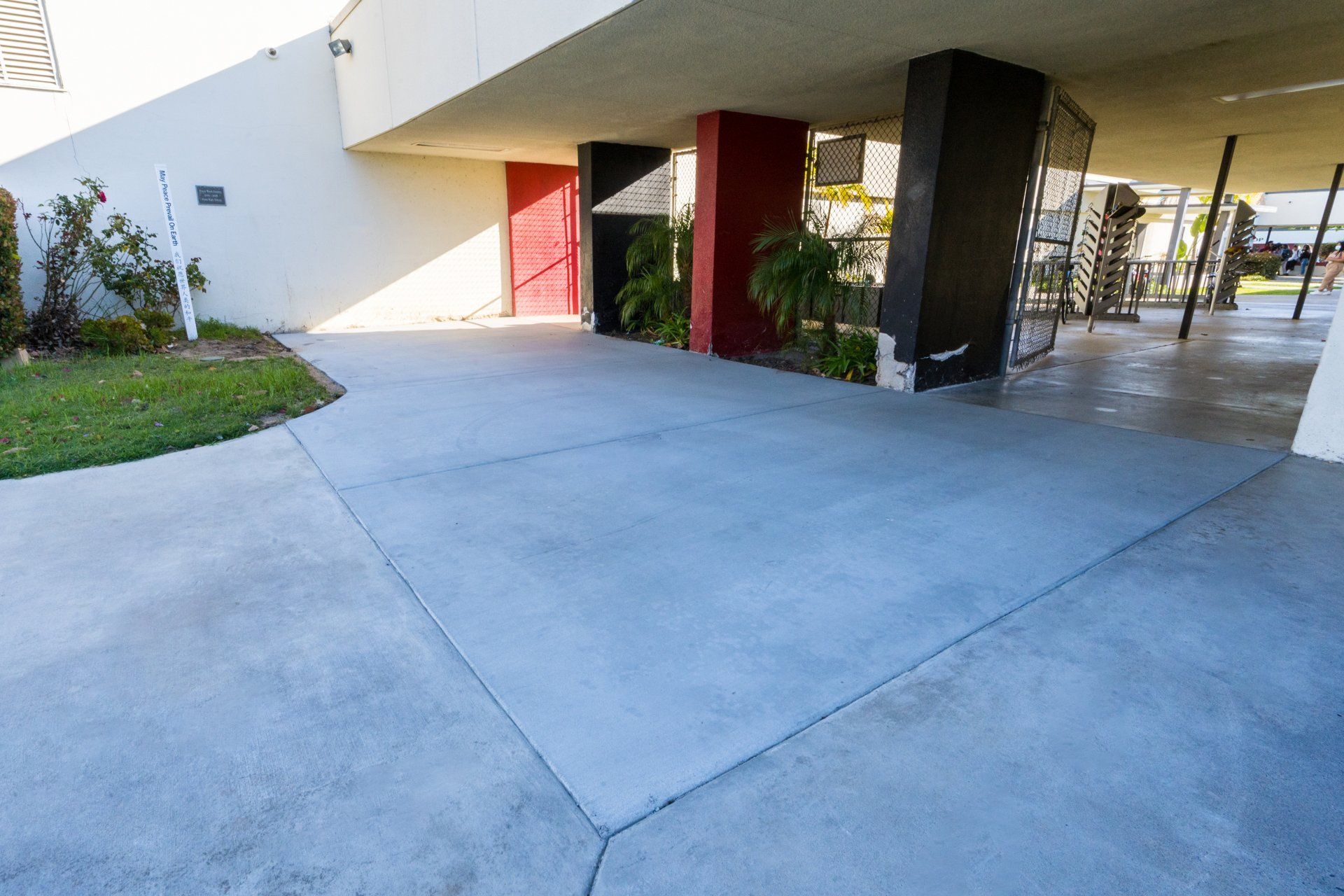 A concrete driveway leading to a building with a red door