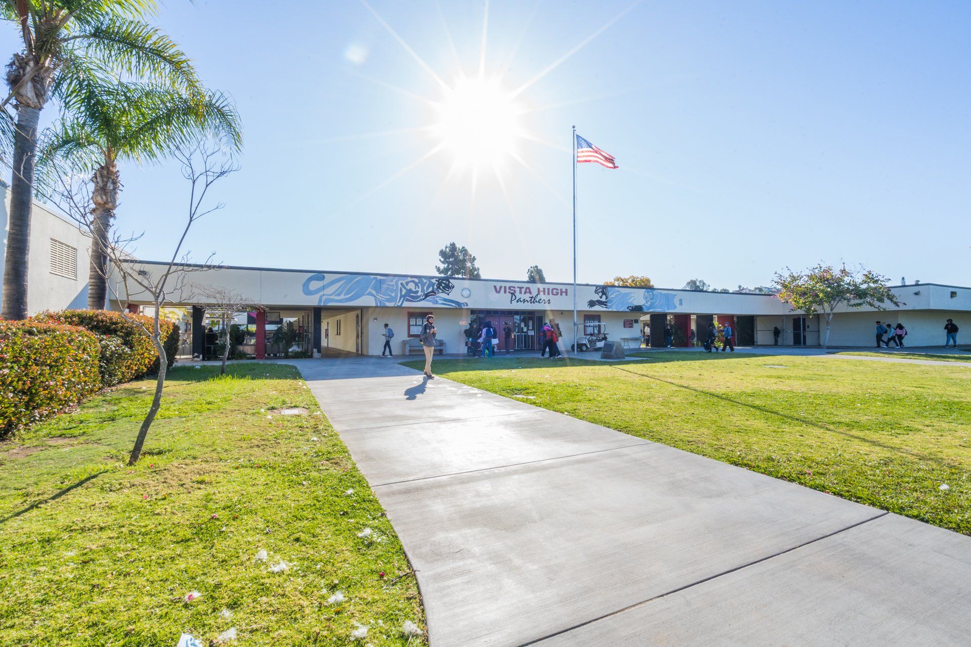 A school building with a flag on top of it and a walkway leading to it.
