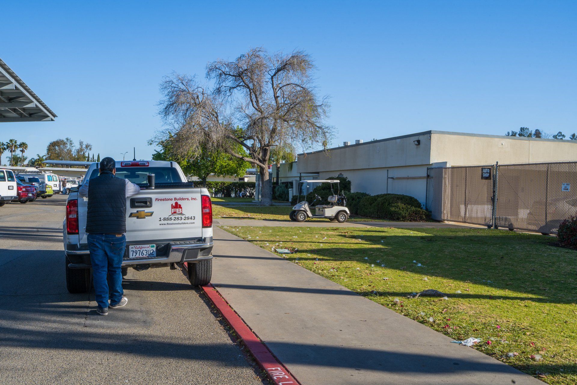 A man is standing next to a white truck in a parking lot.
