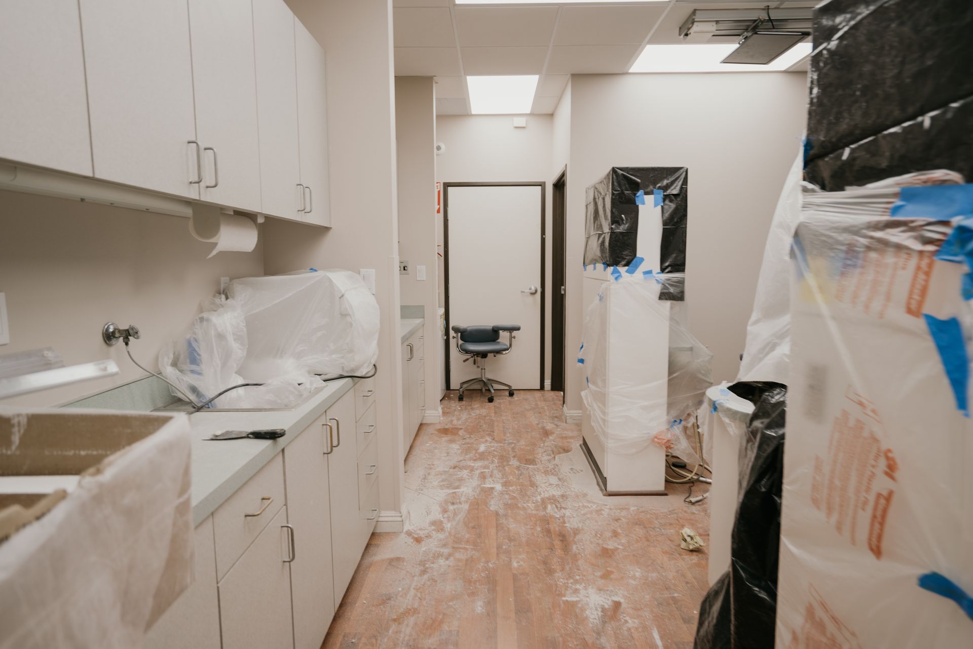 A kitchen with white cabinets and wooden floors is being remodeled.