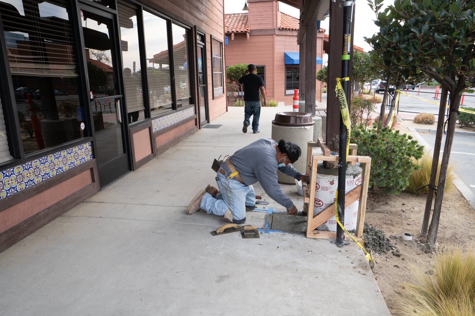A man is working on a sidewalk outside of a building