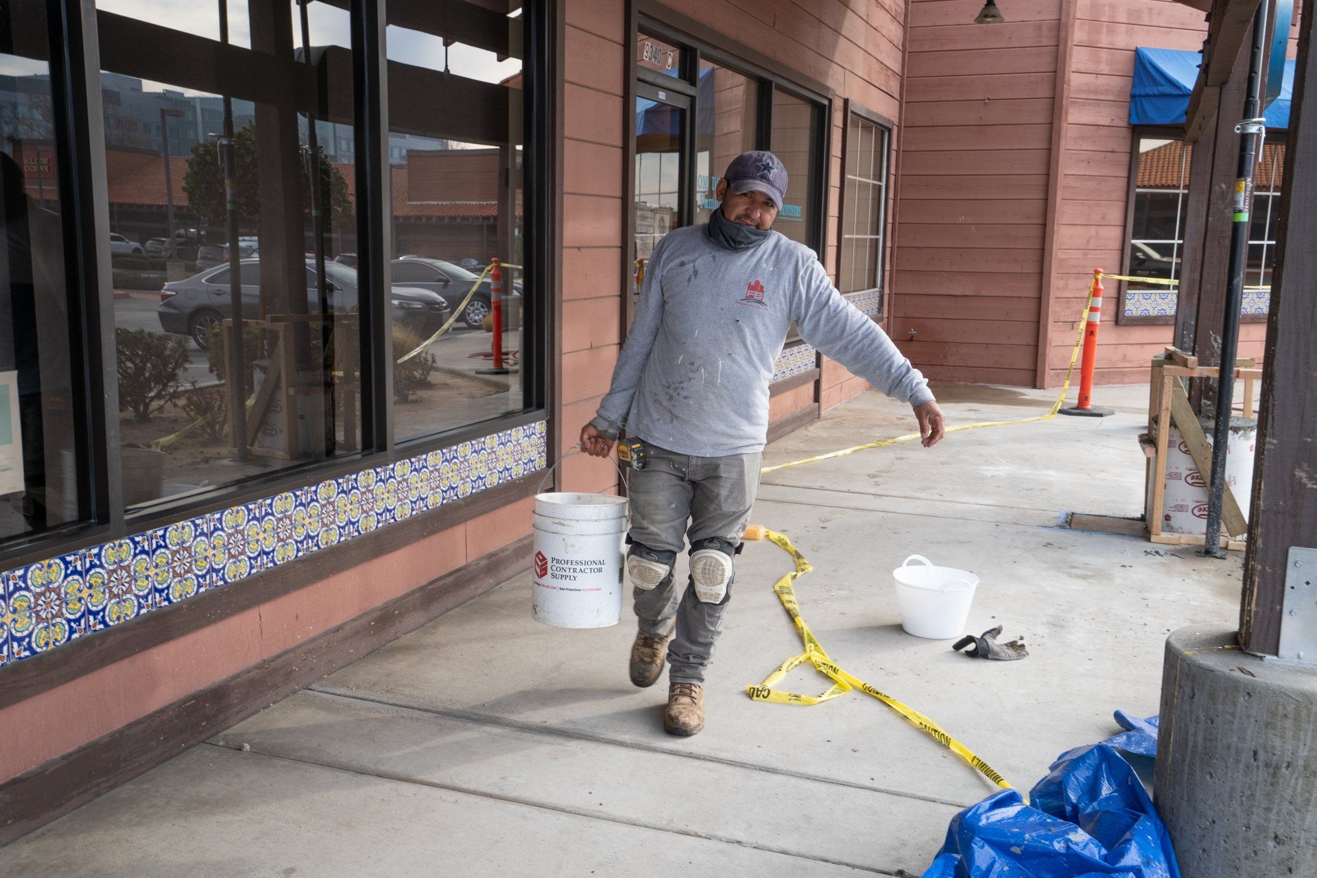 A man is walking down a sidewalk holding a bucket.