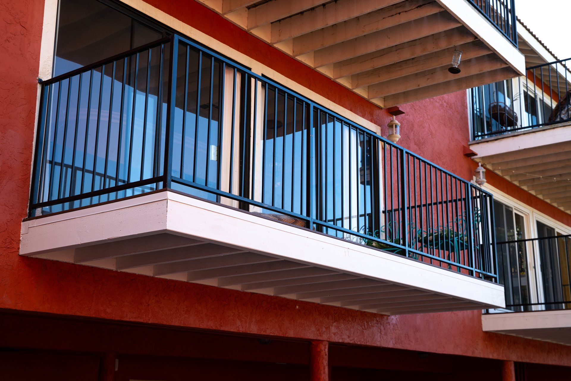 A balcony on a red building with a blue railing