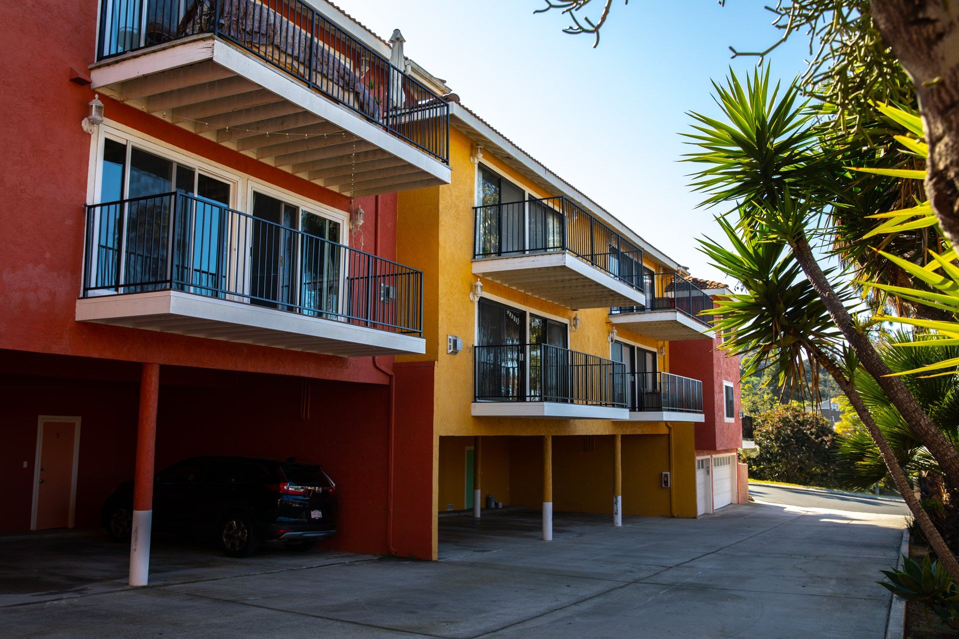 A car is parked in front of a building with balconies