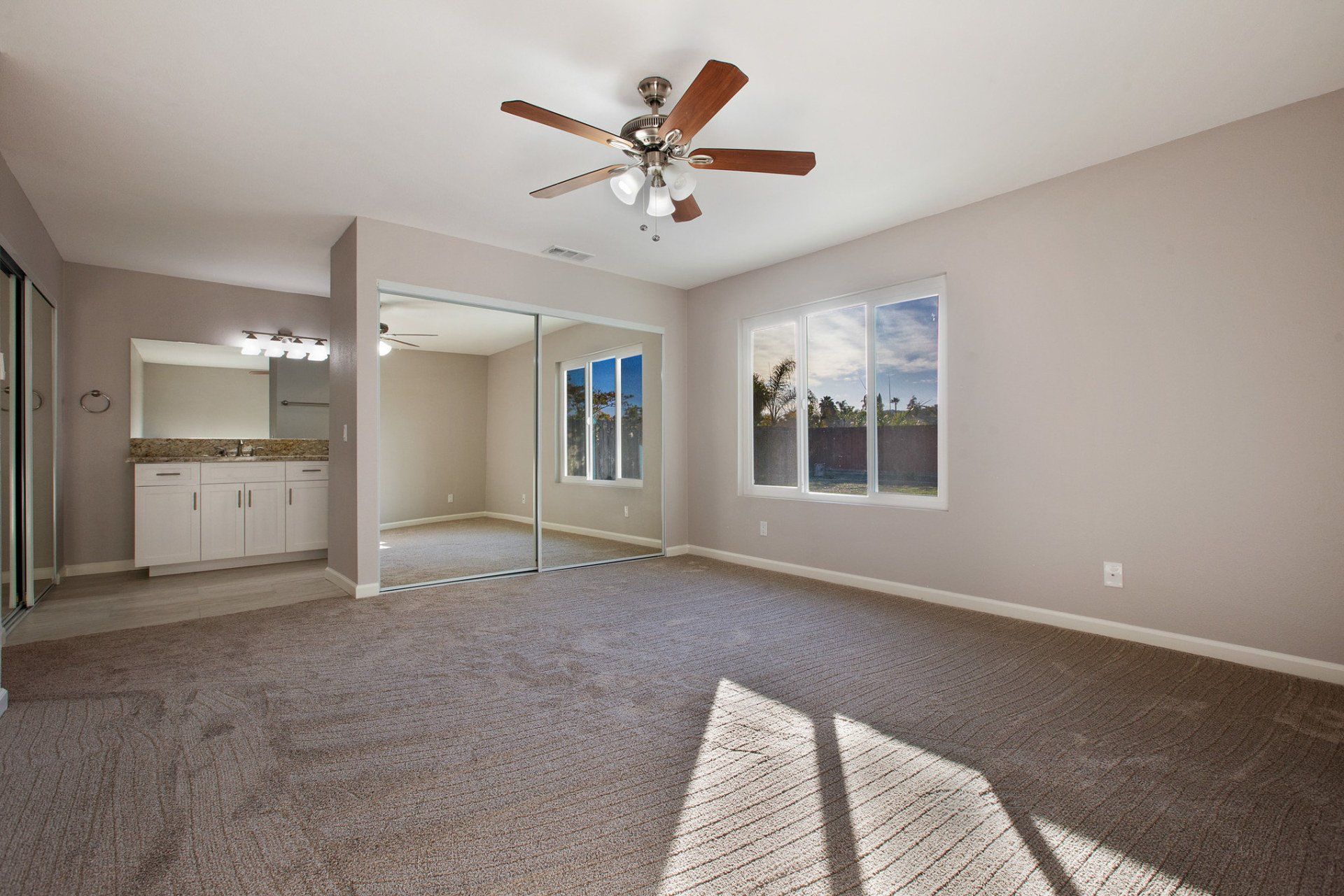 An empty room with a ceiling fan and sliding glass doors