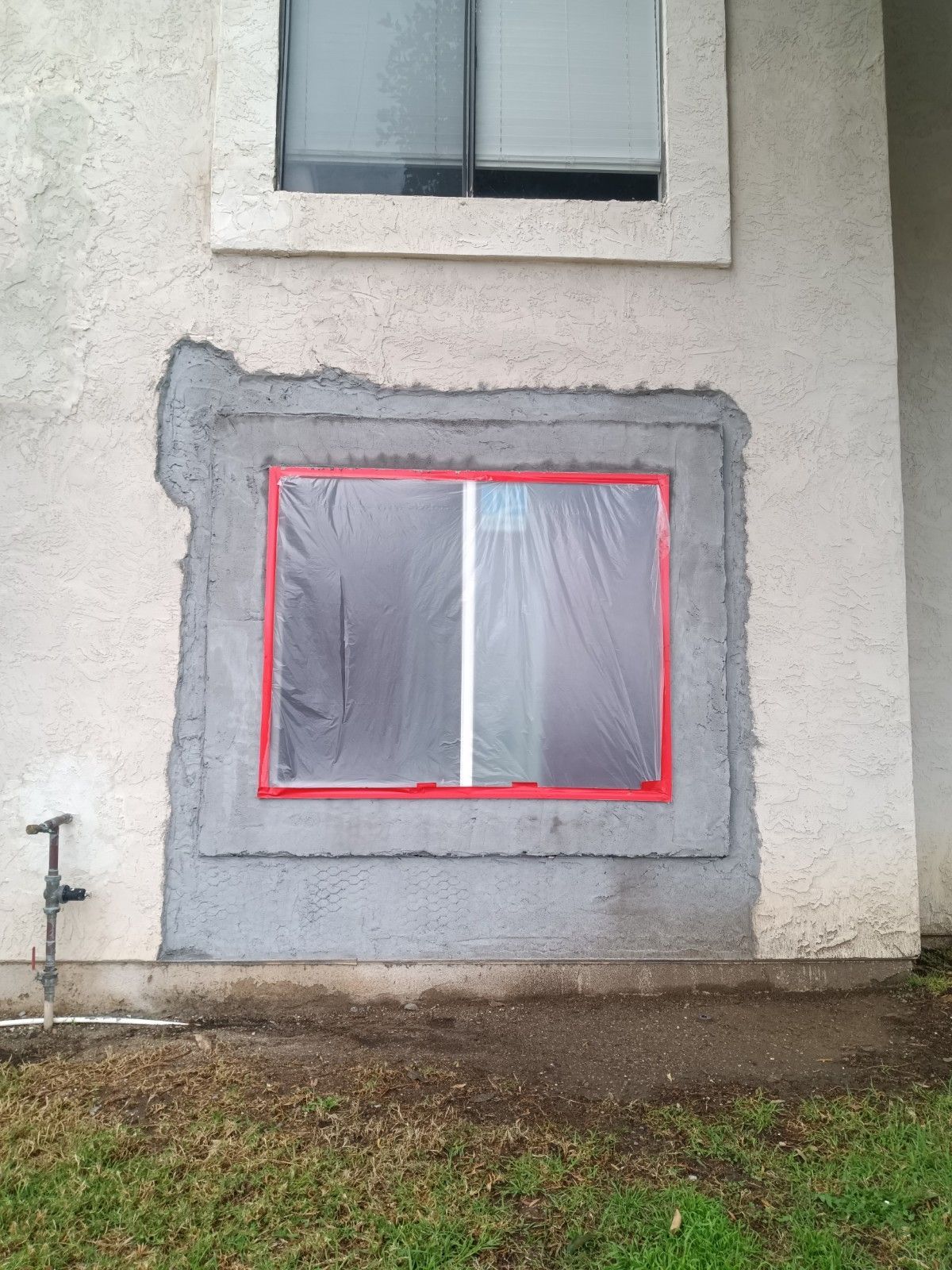 A window on the side of a building with a red tape around it