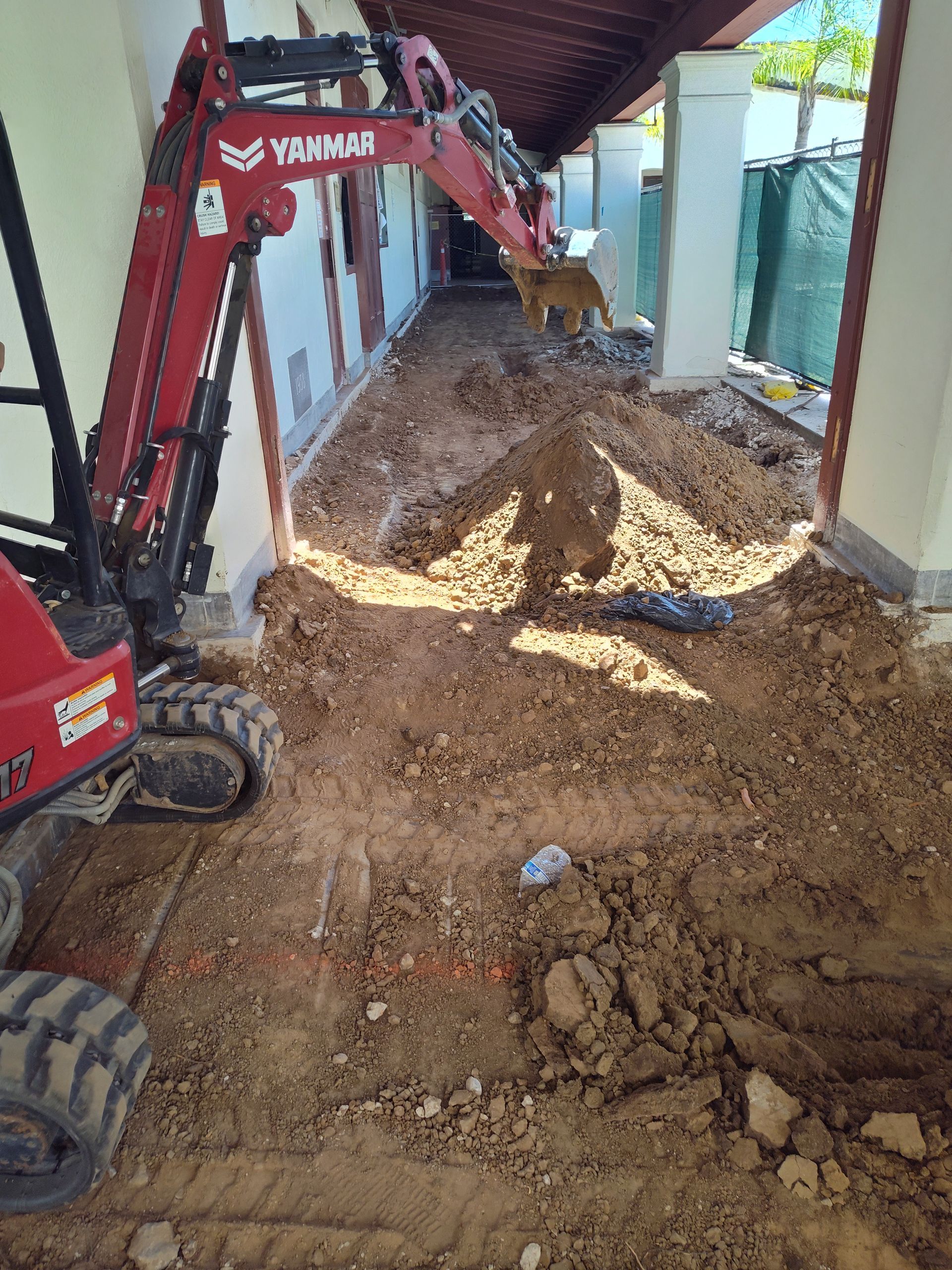 A red excavator is digging a hole in a building.