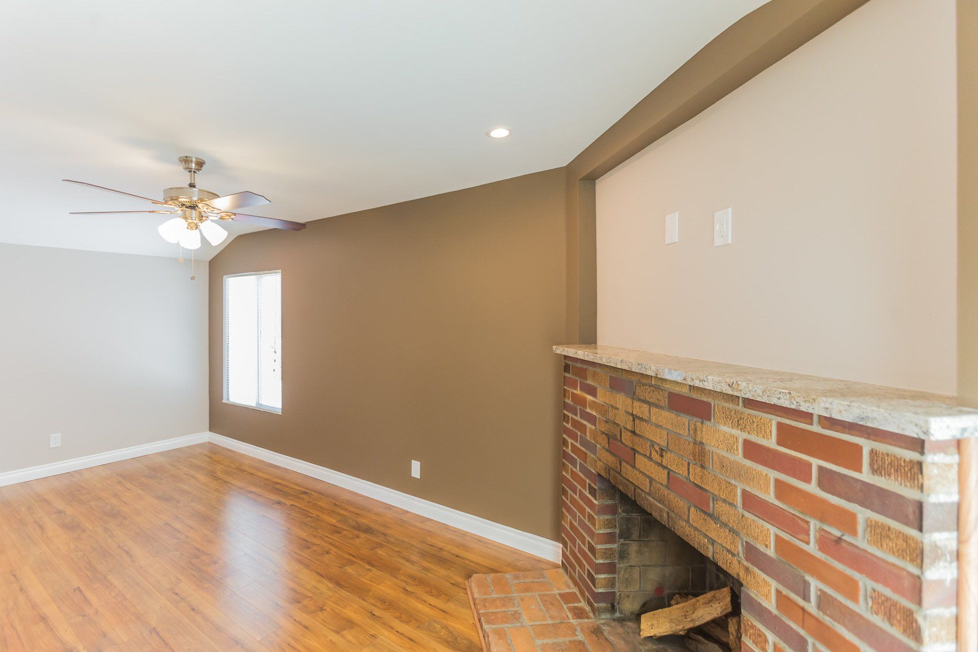 An empty living room with a fireplace and ceiling fan