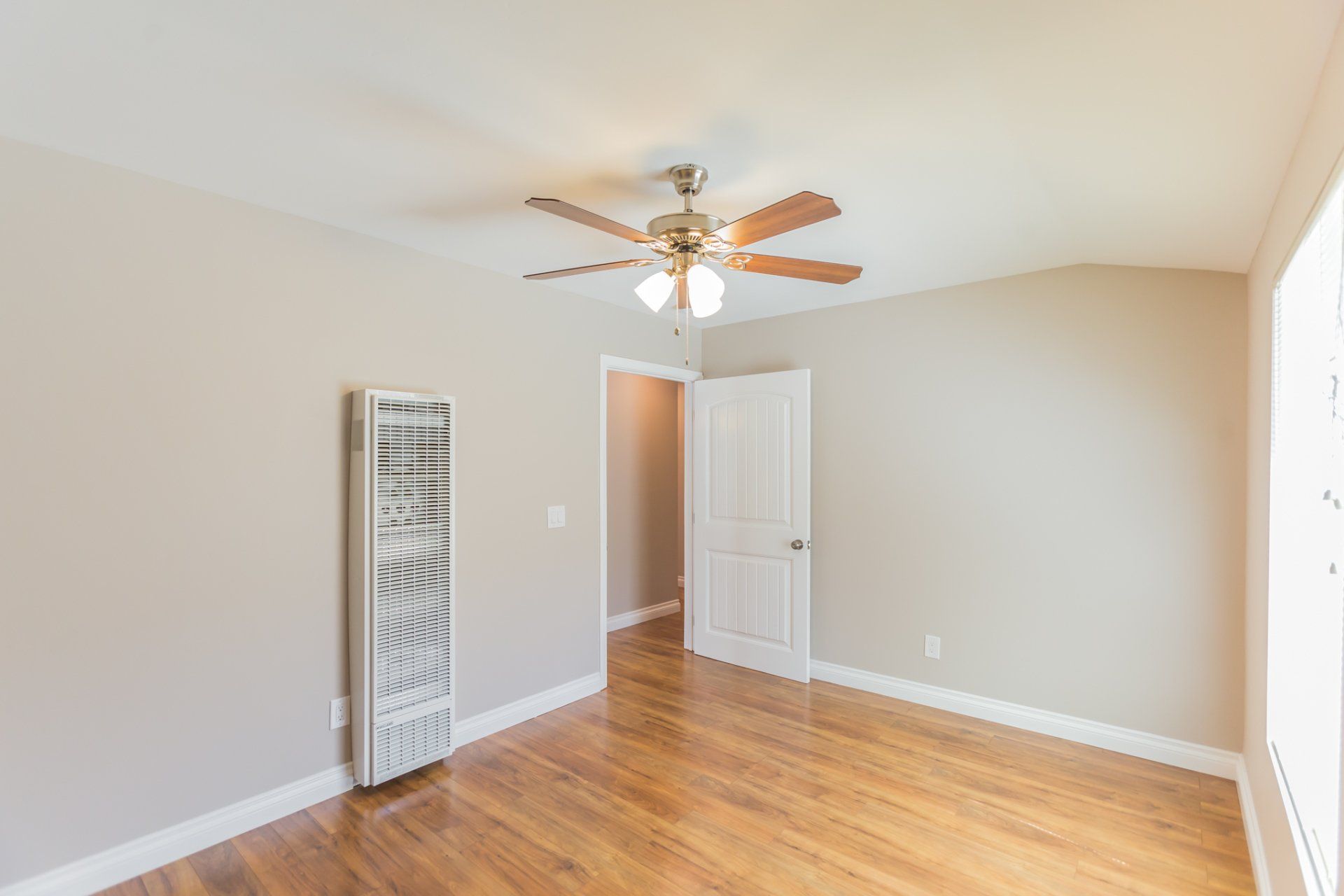 An empty room with hardwood floors and a ceiling fan