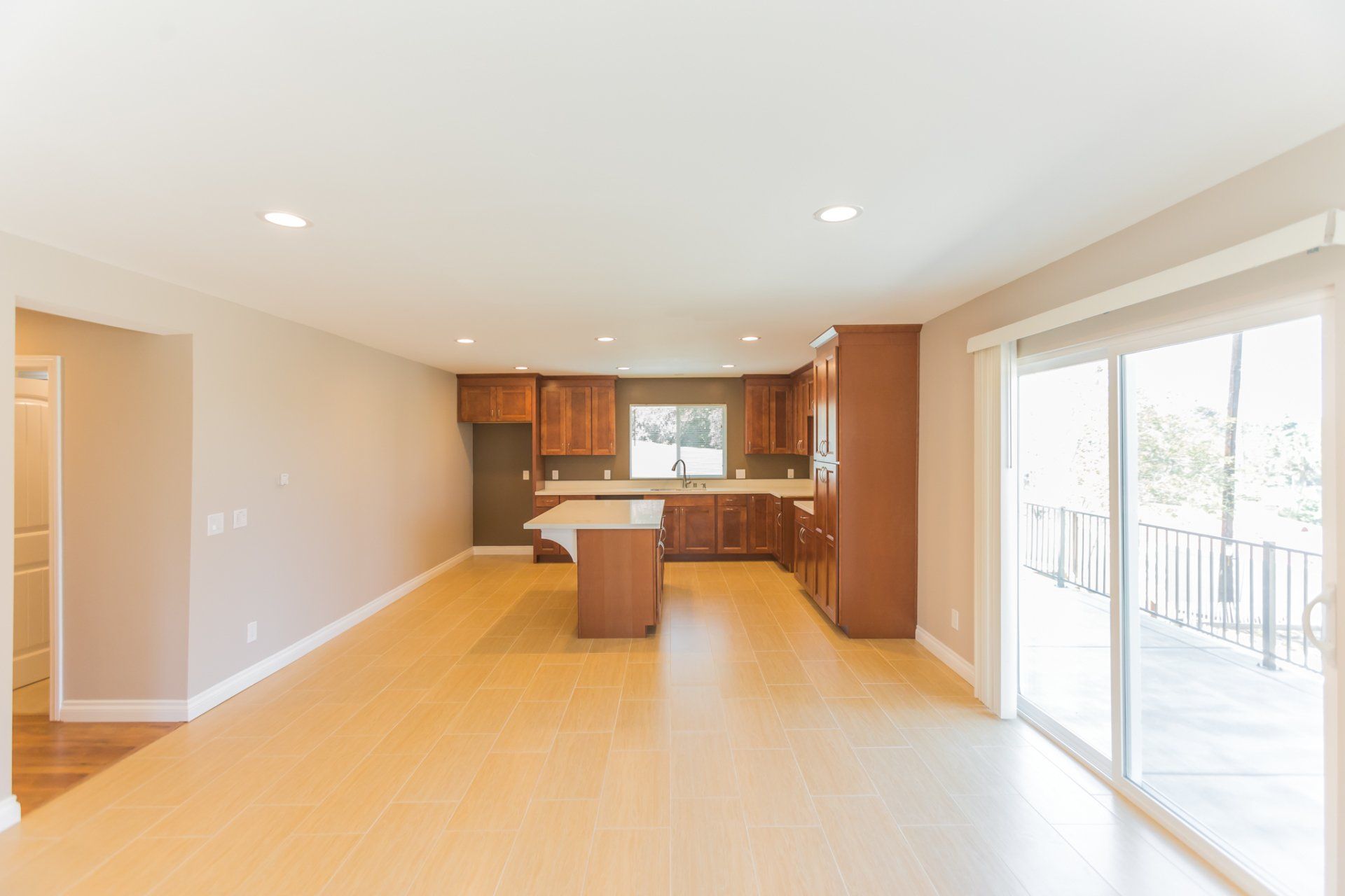 An empty kitchen with wooden cabinets and sliding glass doors