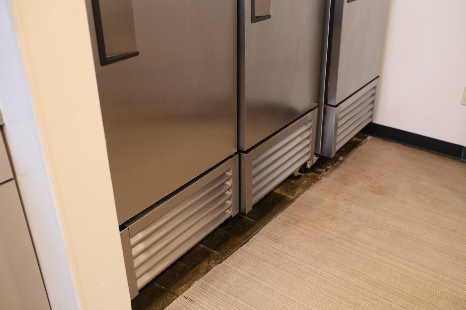 A row of stainless steel refrigerators in a kitchen