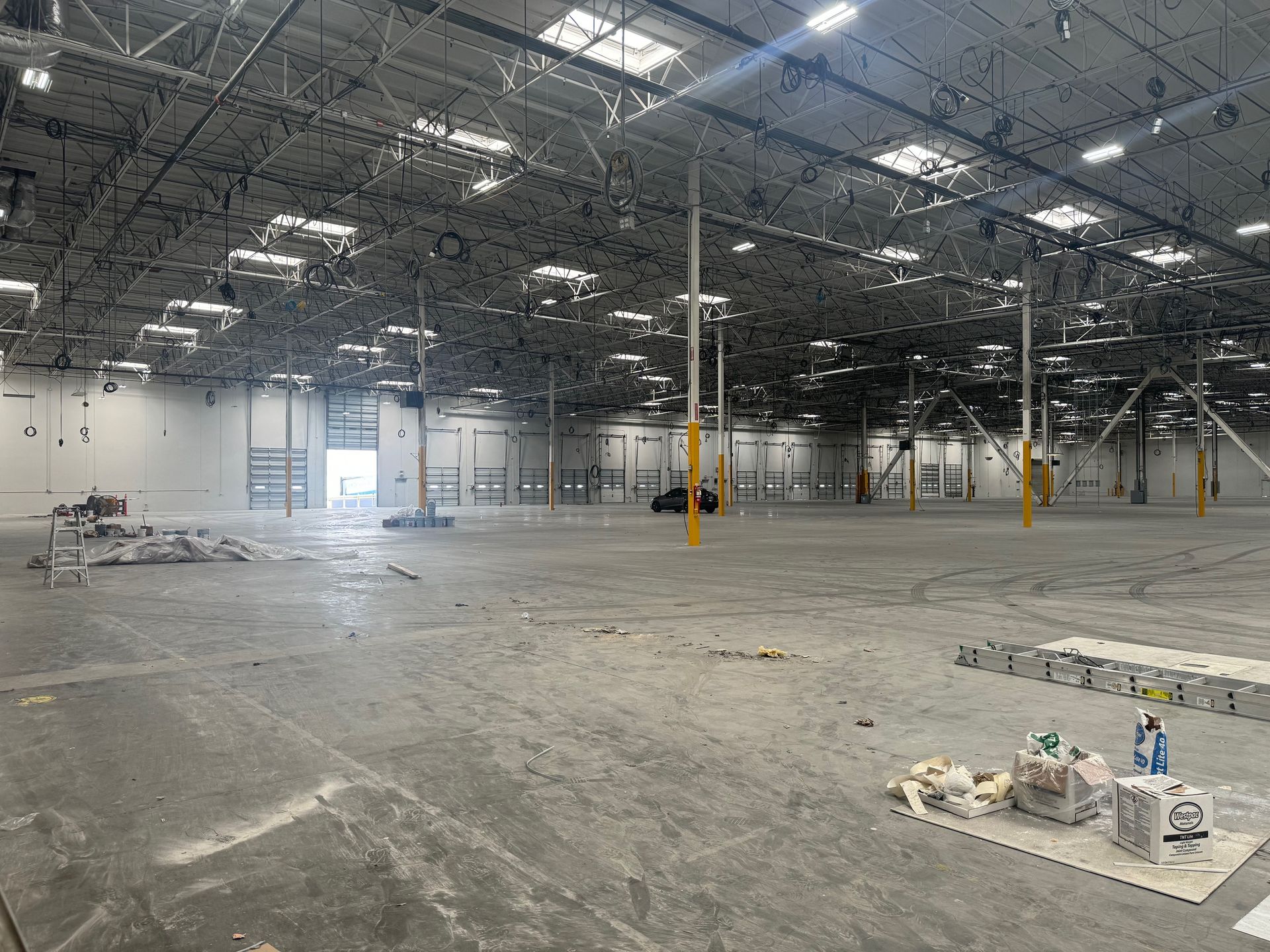 A large empty warehouse with a lot of lights on the ceiling.
