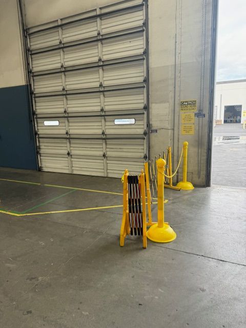 A yellow barrier is sitting in front of a garage door.
