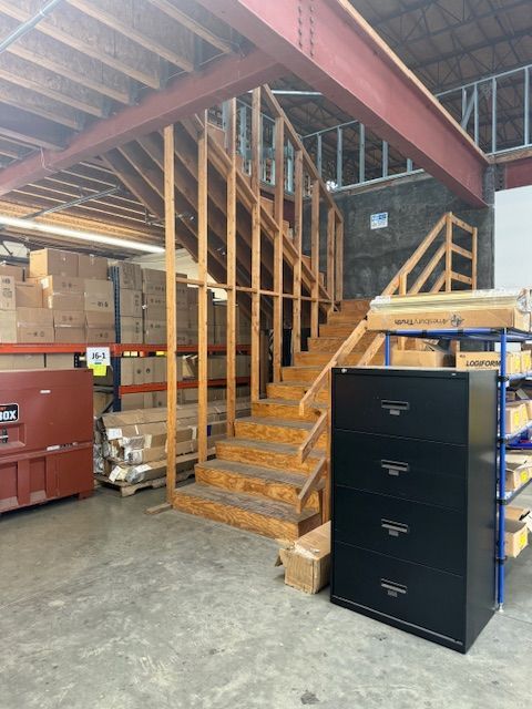 A warehouse with wooden stairs and a black filing cabinet