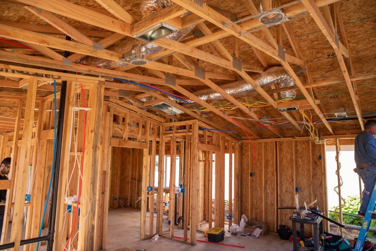 A man is standing on a ladder inside of a house under construction