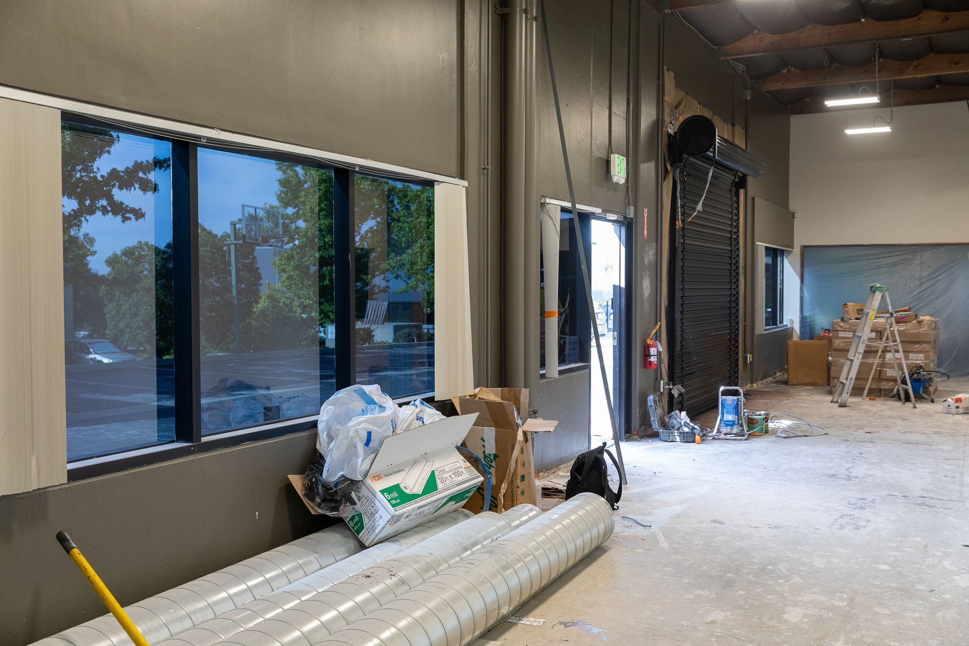 A large empty warehouse with a lot of windows and a mop on the floor.