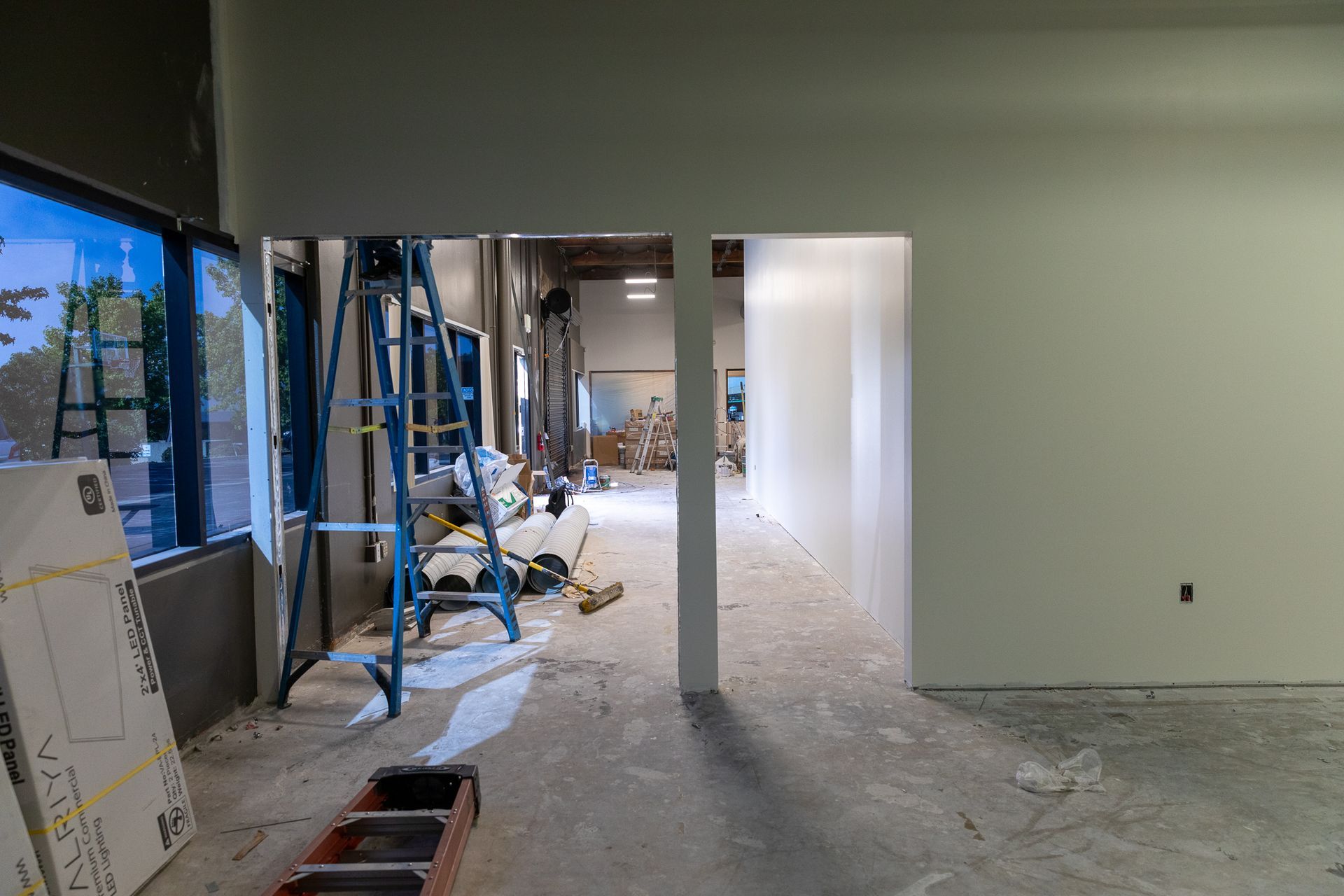 A large room with a ladder in the middle of it is being remodeled.