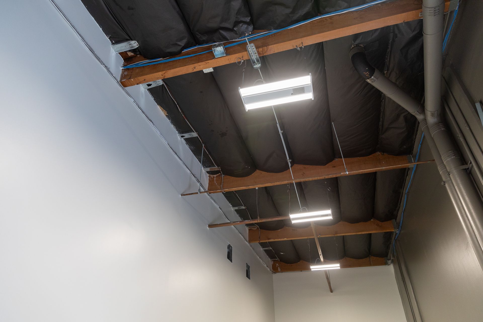 The ceiling of a building with a lot of pipes hanging from it.