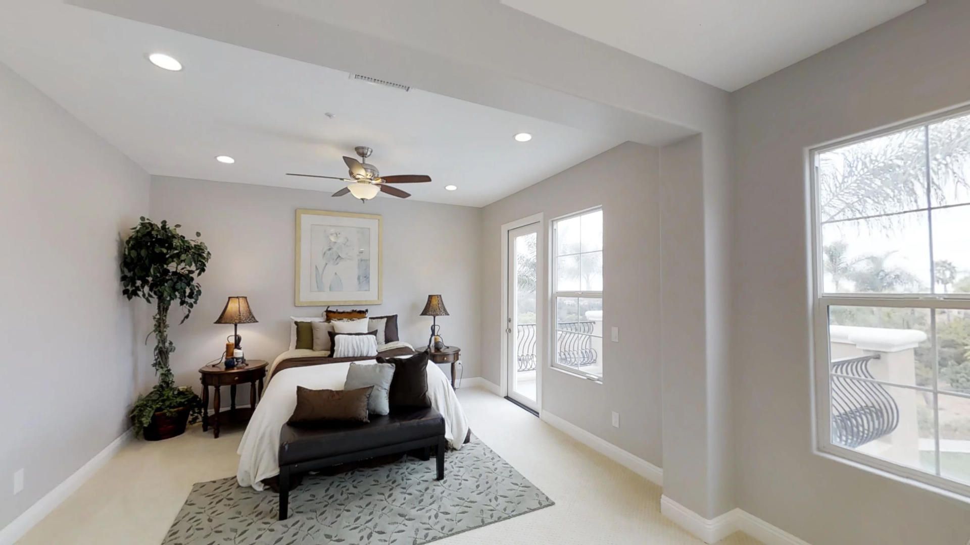 A bedroom with a bed , bench , lamps , and a ceiling fan.