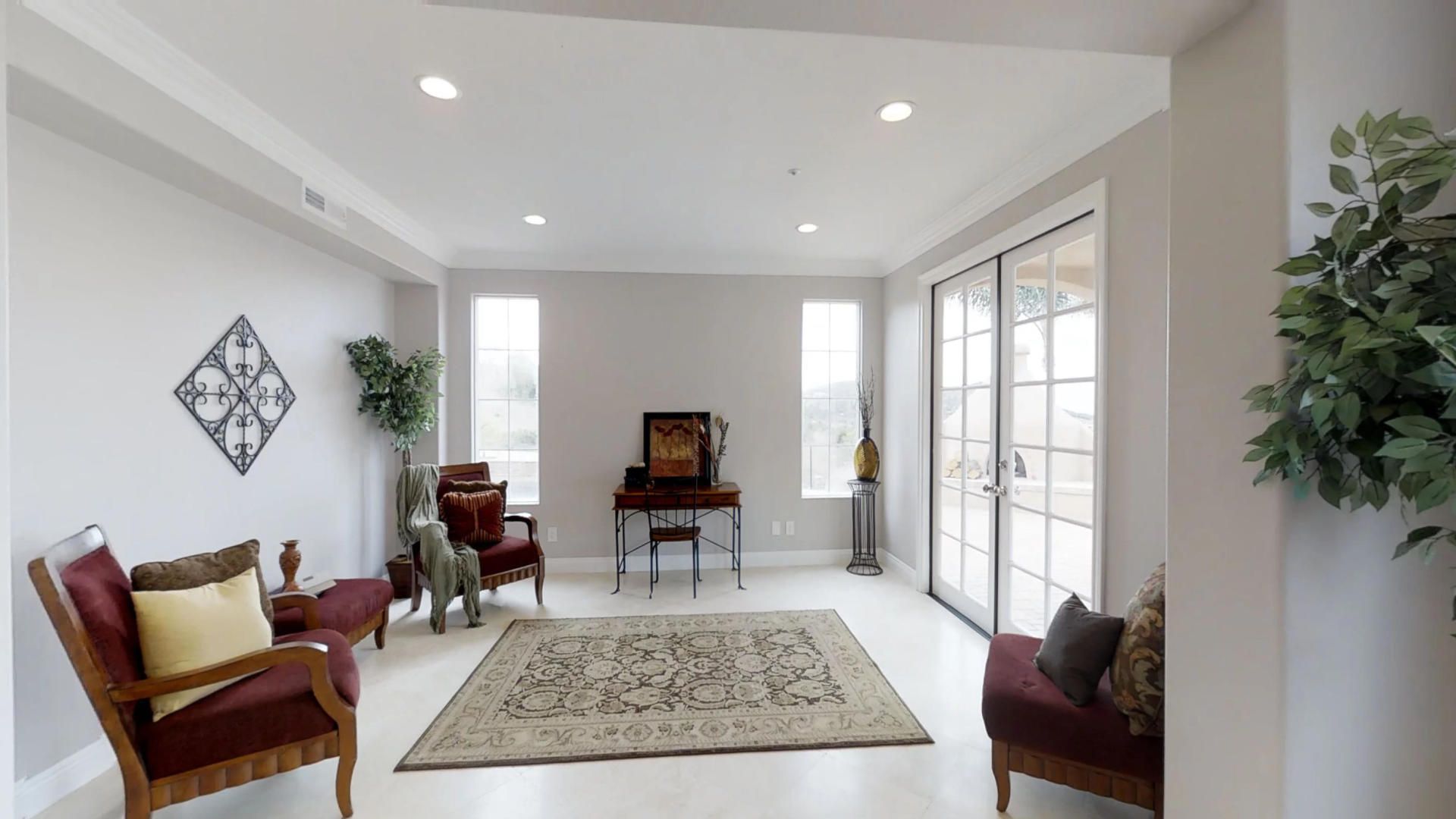 A living room with a rug , chairs , and a clock on the wall.