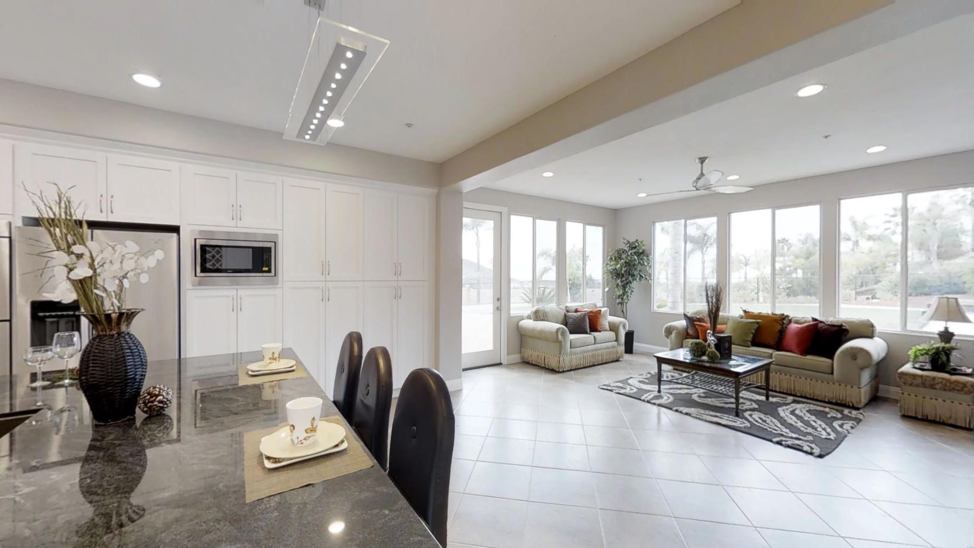 A living room and dining room in a house with a lot of windows.