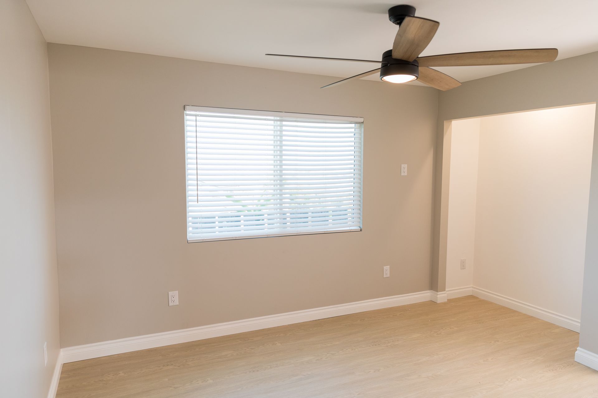 An empty room with a ceiling fan and a window.