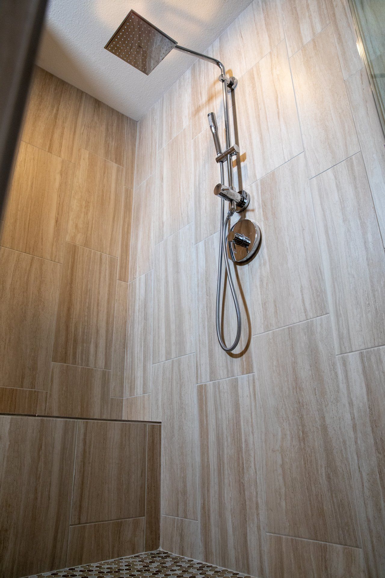 A shower head is hanging from the ceiling in a bathroom