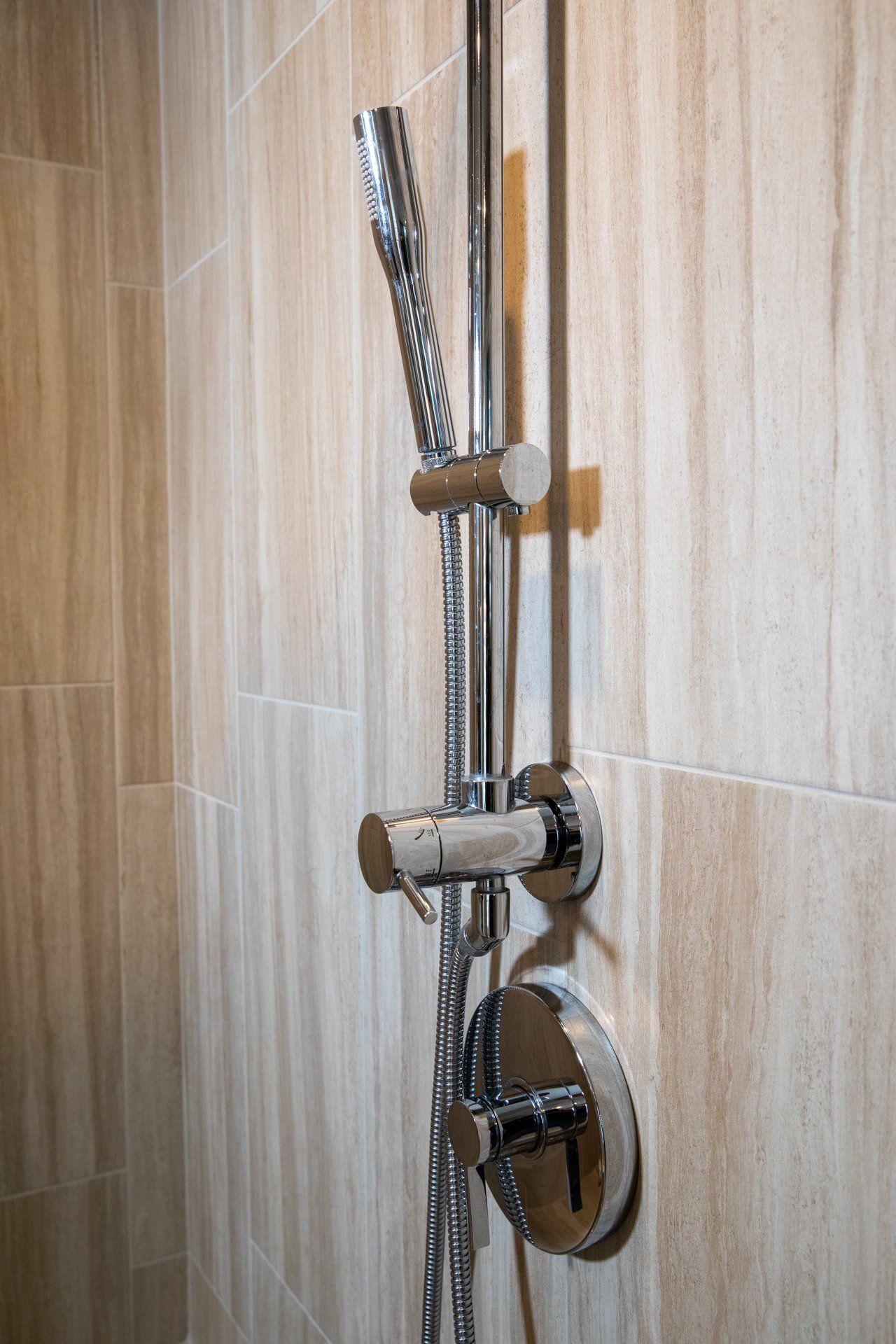 A close up of a shower head on a tiled wall