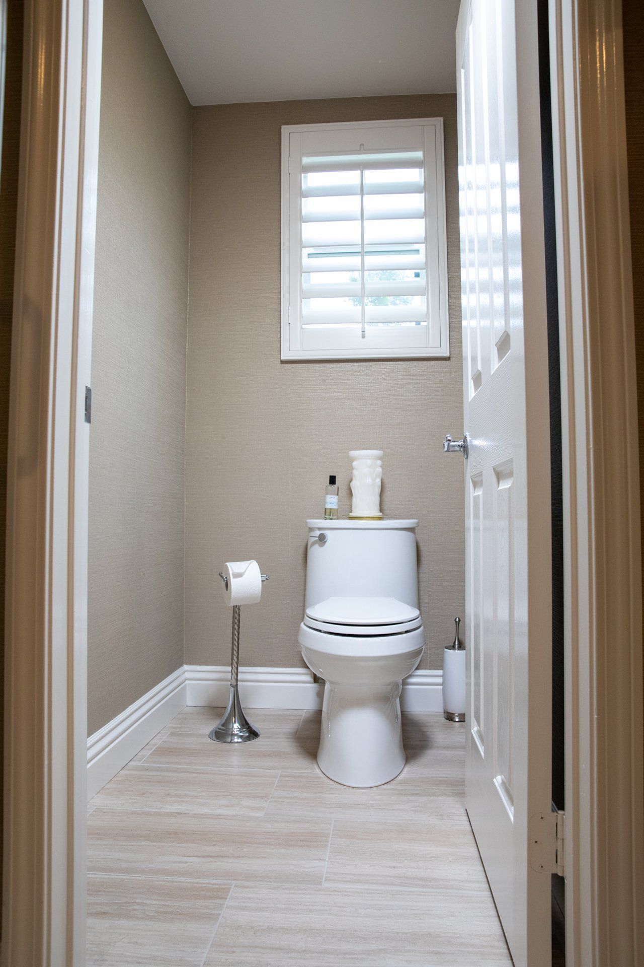 A toilet in a bathroom next to a window