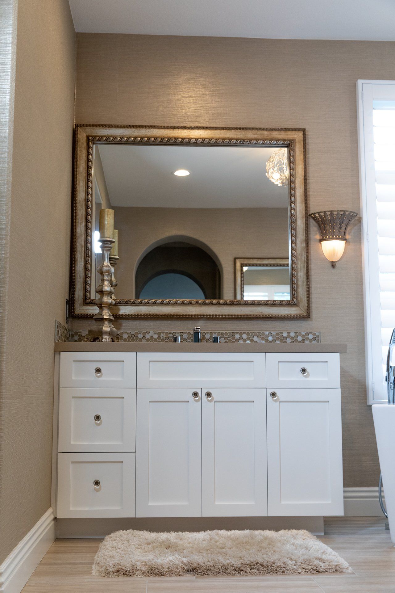A bathroom with white cabinets and a large mirror